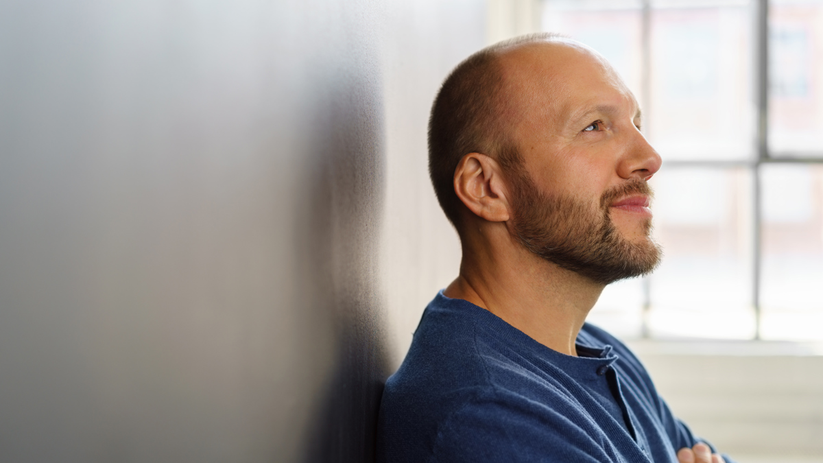 En man lutar sig mot en vägg och reflekterar.