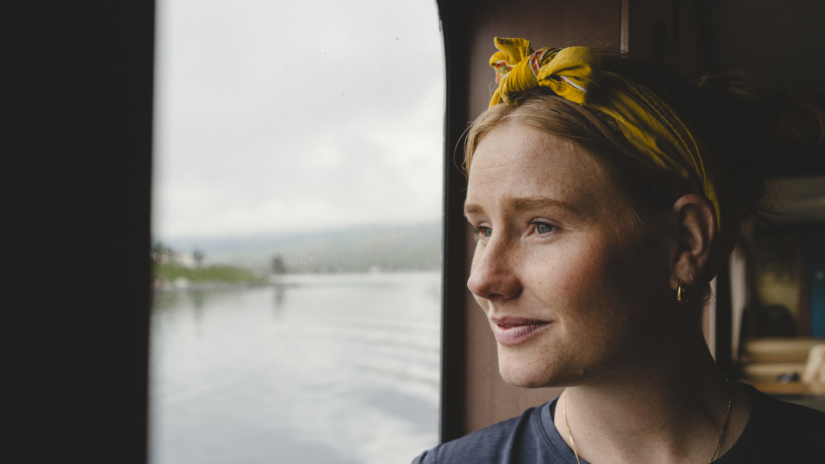 Ung kvinna tittar ut genom ett fönster.